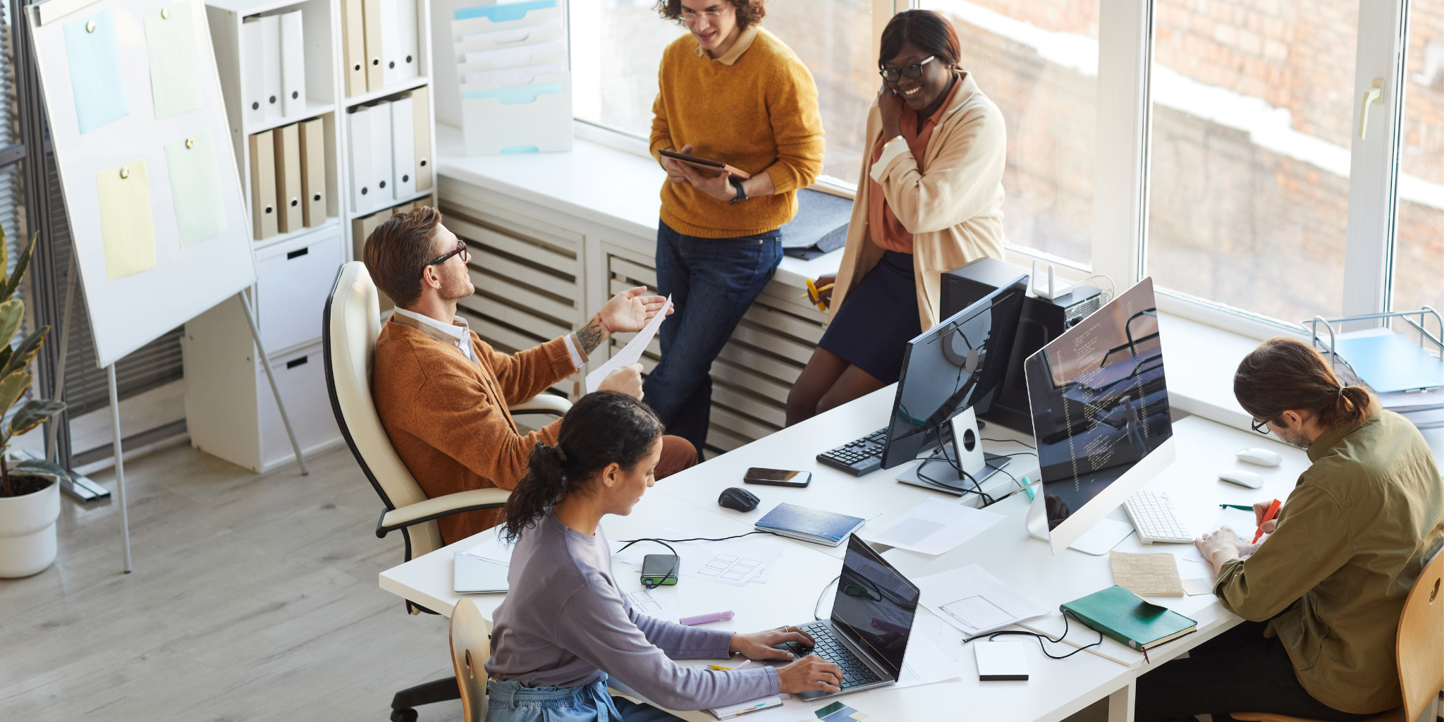 product dev A group of people gathered around a desk with computers and papers